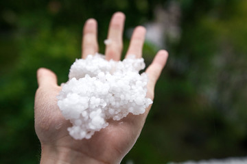 Holding freezing granulated hail ice crystals, grains in hands after strong hailstorm in autumn, fall. First snow in early winter. Cold weather. 