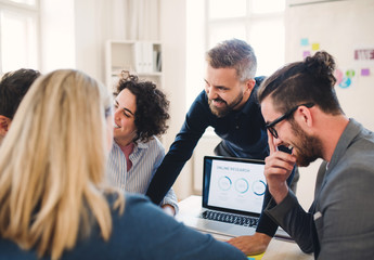 Group of young businesspeople with laptop working together in a modern office.