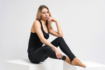 Fototapeta premium Concept portrait of a beautiful blonde girl smiling on a white background advertises product. She is right in front of the camera and shows different emotions.