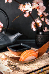 Delicious Sushi Nigiri with Salmon. Dish decorated with a sprig of cherry blossoms. Traditional Japanese cuisine