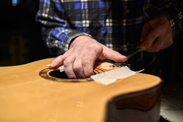 Fototapeta na wymiar Fastening the neck to the Soundboard of the guitar. Removing the varnish from the Soundboard.