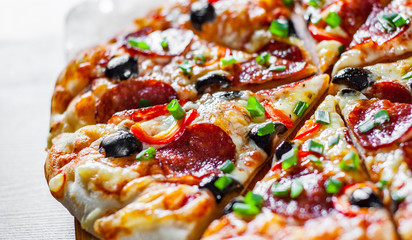 Pizza with Mozzarella cheese, pepperoni, tomato, pepper, olive, salami. Italian pizza on wooden table background