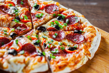 Pizza with Mozzarella cheese, pepperoni, tomato, pepper, olive, salami. Italian pizza on wooden table background