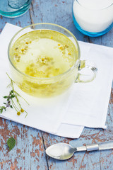 Fresh chamomile blossom tea in a glass cup on a wooden table, healthcare and healthy eating concept