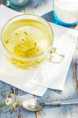 Fresh chamomile blossom tea in a glass cup on a wooden table, healthcare and healthy eating concept