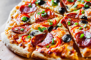 Pizza with Mozzarella cheese, pepperoni, tomato, pepper, olive, salami. Italian pizza on wooden table background
