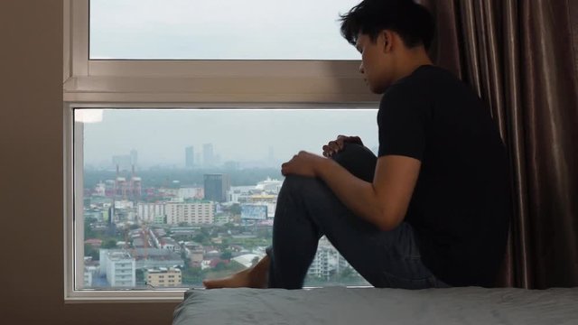 Man hugging knees and cry at windows