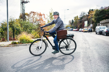 Active senior man with electrobike cycling outdoors in town.