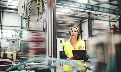 Industrial woman engineer with headset in a factory, working. Copy space.