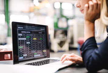An industrial woman engineer in a factory using laptop.