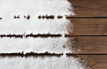 Wooden floor covered by snow melting in the sunlight. Background with copy space.