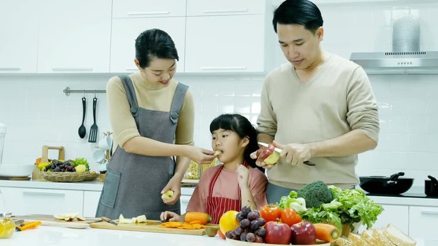 Little girl help her mother and father to preparing food at kitchen. Mother and father training little girl to preparing food. People lifestyle concept.