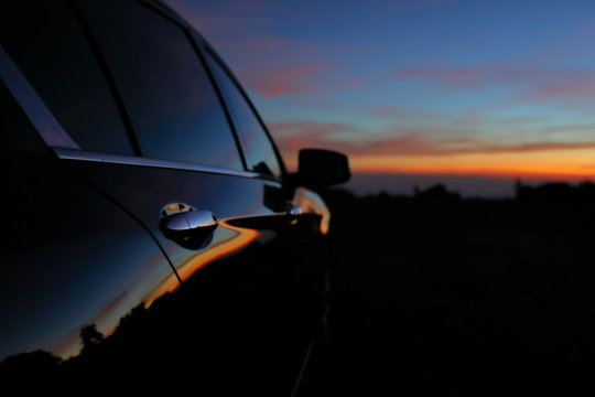 black vehicle car with reflection of landscape sunset dramatic dusk sky