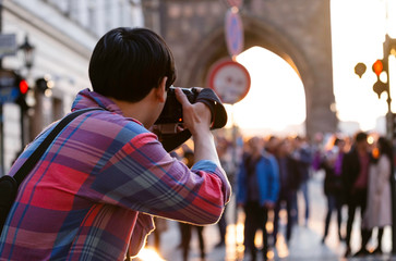 Back view of Street photographer journalist on street in the evening at Charles Bridge,Prague