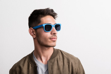 A confident young hispanic man with sunglasses in a studio.
