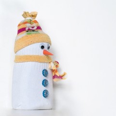 Cute snowman toy, made of white and yellow socks, with hat and scarf, textile figure. Handmade home winter decoration. Do it yourself. White background, copy space for text.