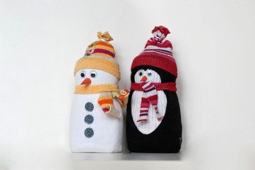 Cute snowman and penguin toys, made of white black and colorful socks, with hat and scarf, textile figures. Handmade home winter decoration. Do it yourself. White background, copy space for text.