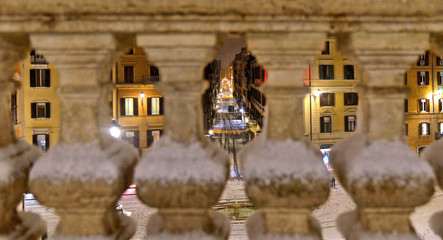 Blurred Night view city with snowfall on square, houses and old architecture seen from spanish square steps marble fence completely covered by snow Rome, Italy
