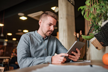 Young man using digital tablet in the cafe. Low angle view.