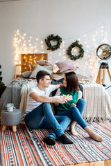 Naklejka premium Szczęśliwa kochająca para mężczyzna i kobieta przytulanie w tle jest świątecznym wystrojem w sypialni.