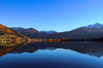 Beautiful view on the crystal clear water lake and snow covered top of mountains in Zell am See in Austria during late fall
