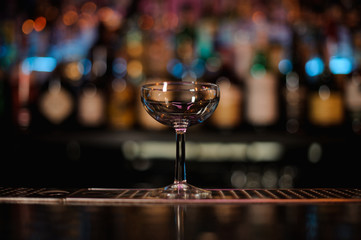 Empty cocktail glass standing on the bar counter