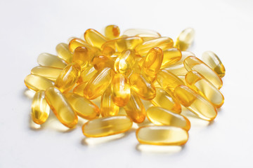 Fish oil capsules in yellow on a white background. Health care, food supplements for beauty. The benefits of Omega 3