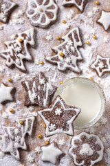 Christmas homemade chocolate cookies decorated with icing and powdered sugar with milk on a wooden background, top view