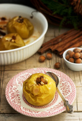 Baked apples with raisins, hazelnuts and cinnamon on wooden background. Rustic style.