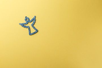 Christmas decoration angel on yellow background. Symbolic image. Christmas background. Copy space. Top view. Flat lay. Concept holiday
