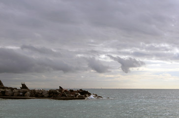 Cielo tempestoso con frangiflutto mare e vele all'orizzonte