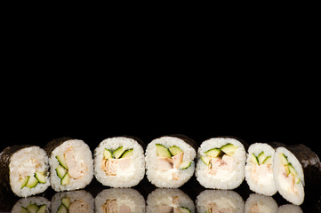 seven delicious sushi rolls in reflection isolated on black background