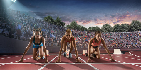 Female athletes sprinting. Three women in sport clothes on starting line prepares to run at the...