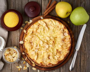 Cheesecake, apple pie, curd dessert with polenta, apples, almond flakes and cinnamon on dark wooden...