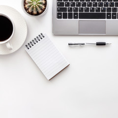 Styled stock photography white office desk table with blank notebook, computer, cactus, supplies and coffee cup. Top view with copy space. Flat lay..