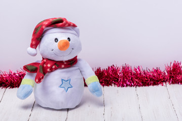 Funny snowman in a red hat and scarf on a white background