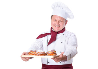 Chef confectioner holds on a tray fresh buns on a white background. Male cook.