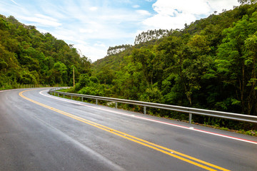 Fototapeta na wymiar New asphalt road with bike path, forest next to it, blue sky with clouds, Dr. Pedrinho, Santa Catarina