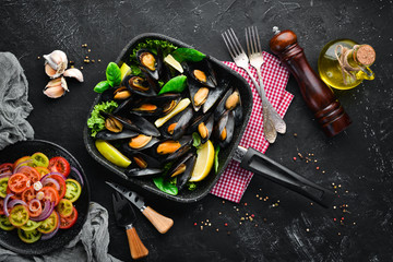 Fried mussels in a frying pan. Top view. Free space for your text. On the old background.