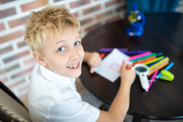 Boy is painting on a white sheet of paper