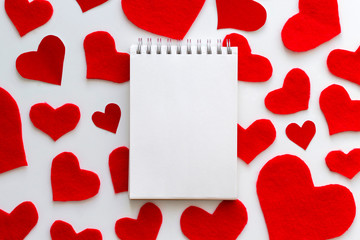 Notebook on the red felt hearts background. Valentine's Day concept. Top view, copy space, mock up