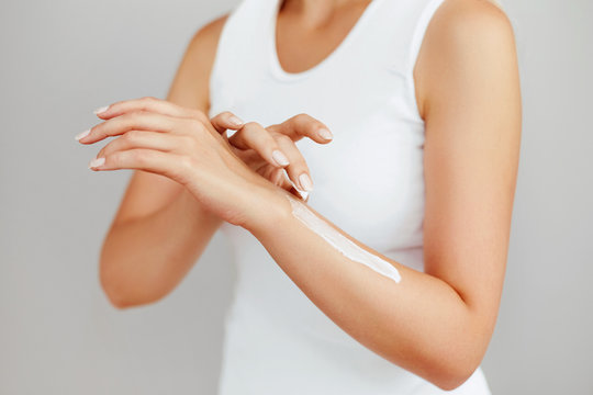 Closeup shot of woman hands holding cream and applying moisturizing hand cream. Beautiful female hands with cream. Hand Skin Care. A woman uses body lotion on your arms. Beauty And Body Care Concept