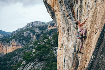 woman climbs a rock in Greece and beautiful forest and cliff landscape on the background