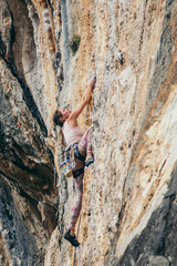 woman climbs a rock in Greece and beautiful forest and cliff landscape on the background