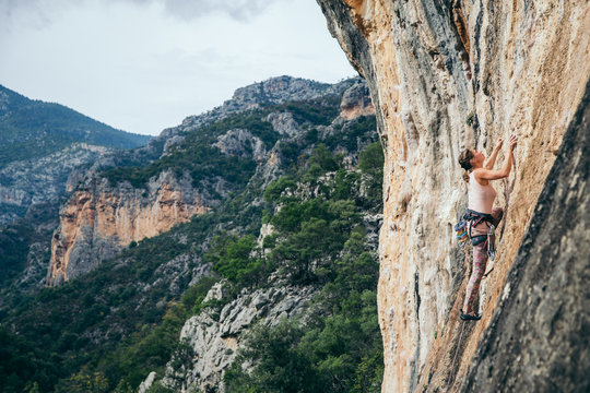 woman climbs a rock in Greece and beautiful forest and cliff landscape on the background