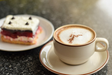 Cappuccino coffee served with raspberry layer cake on a cold morning at Cafe'. 