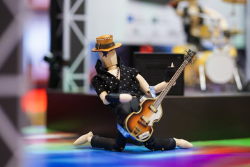 Wooden dummy. A wooden doll on action. Performance of a wooden mannequin as a rock guitarist on stage, kneel down on the stage floor. Entertainment concept of rock music performance.