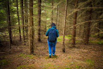 Obraz premium Woman with backpack and blue clothes walking in the forest