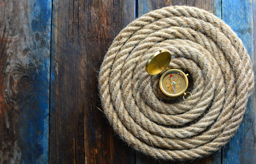 Nautical background with a copy space. Spiral rope and compass on a textured, weathered desk.