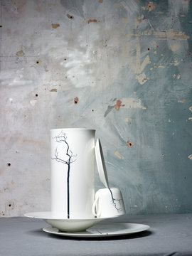 Gestapeltes weisses Porzellan Service mit grafischem Muster vor bemalter Wand